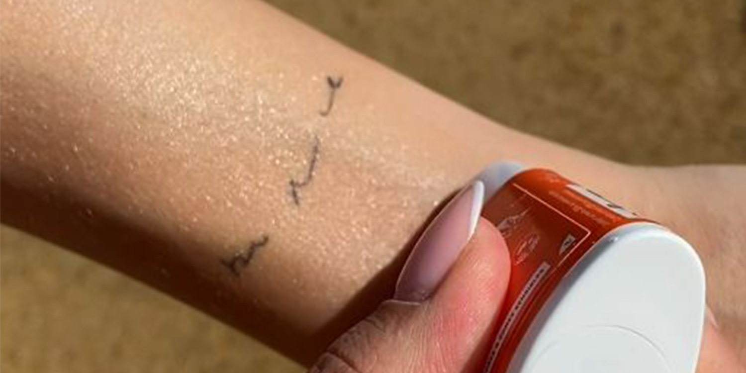 application d'un stick solaire sur un tatouage à la plage