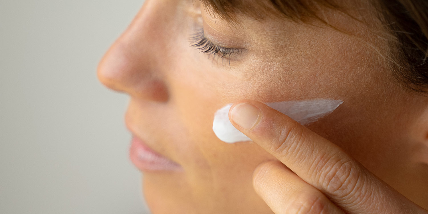 Femme qui s'applique de la crème sur le visage